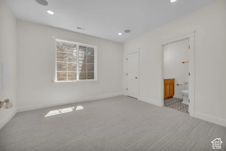 Recessed lighting, light-toned carpeting, and a white trim window