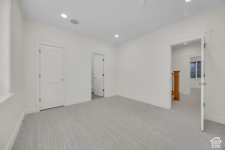 Recessed ceiling lighting, integrated ceiling audio speaker, light-toned carpet flooring, white interior doors, and solid wood stair railing