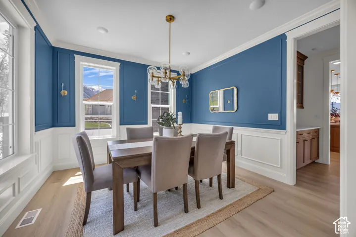 Wood-finish flooring, wainscoting, and a decorative chandelier define this space