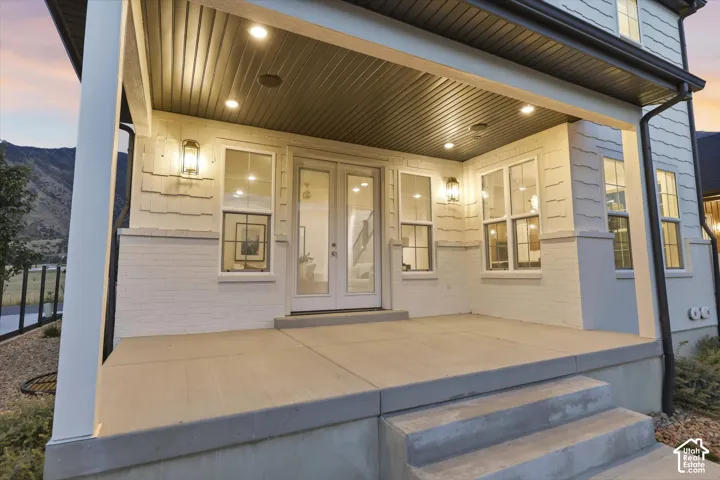 Covered concrete front porch with recessed lighting and two exterior wall sconces