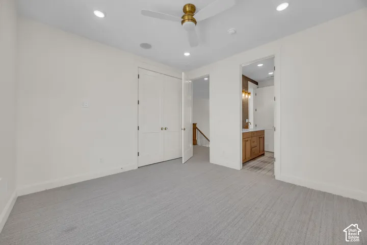 Recessed lighting, ceiling fan, carpeting, double closet doors, and wood-finish vanity with wall sconces