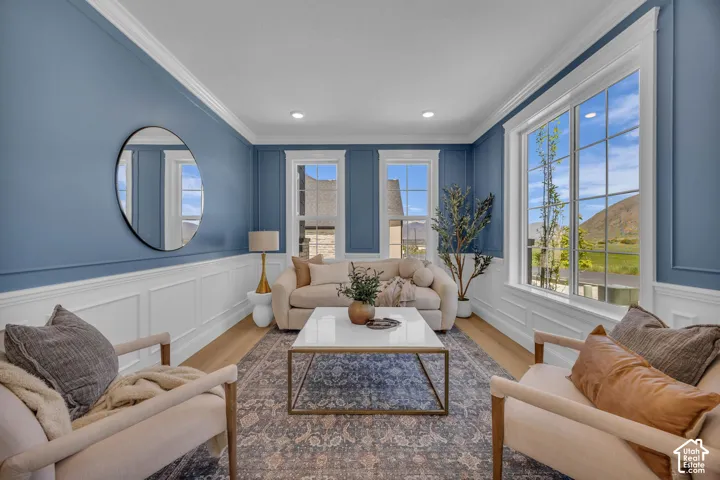 Expansive window framing, crisp white wainscoting, crown molding, wood-finish flooring, and recessed ceiling lighting