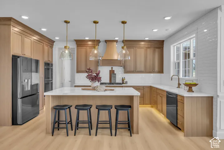 Kitchen featuring wood-finish cabinetry, white subway tile backsplash, a large center island with seating, recessed lighting, and a window above the sink