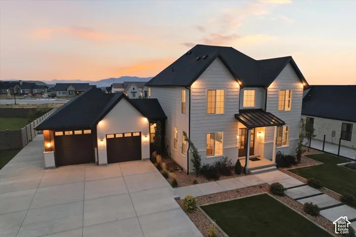 Contemporary exterior with light siding and dark trim, featuring a covered entry, an attached two-car garage, and a concrete driveway