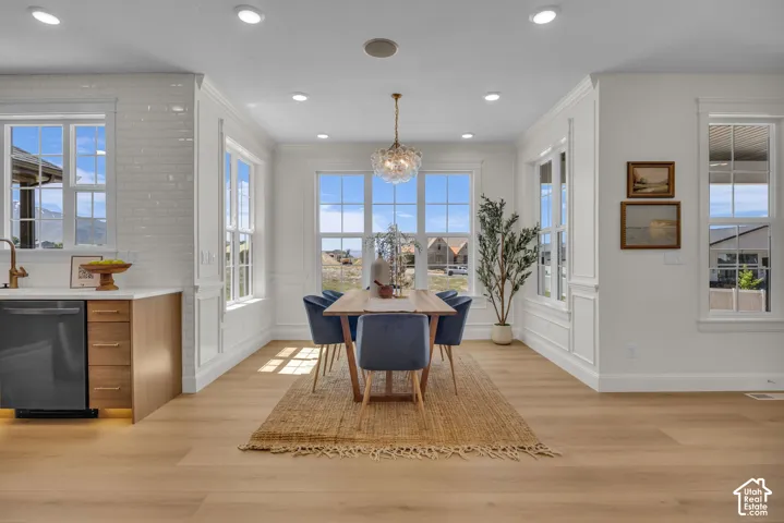 Open-concept dining area with wood-finish flooring, recessed lighting, multiple windows, and a glass orb chandelier