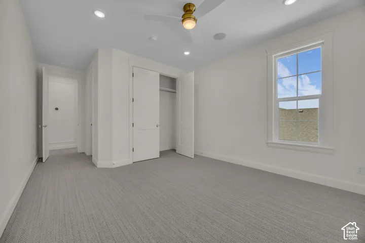 Recessed lighting, ceiling fan, white trim work, light gray patterned carpeting, and white paneled doors