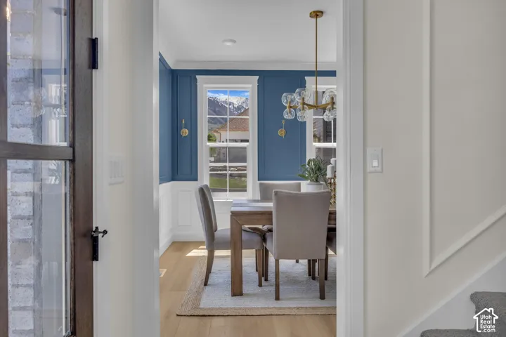Dining space featuring a modern chandelier, wall sconces, wainscoting, and wood-finish flooring