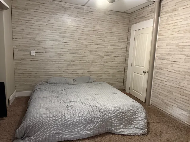 Textured wall covering in a horizontal pattern, white paneled door with brushed nickel hardware, and neutral-toned carpeting