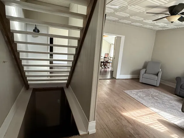 Wood-finish flooring, staircase with open risers, and decorative ceiling tiles