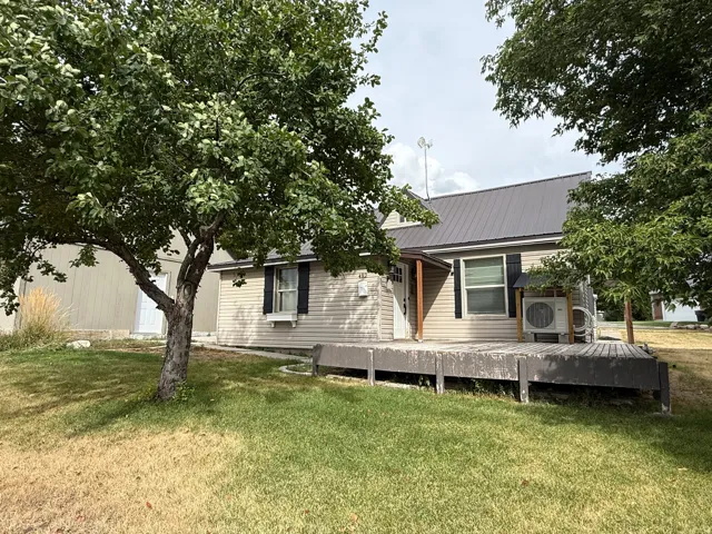 Metal roof, light-colored siding, dark shutters, window box, and an expansive wooden deck