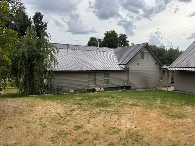 Property featuring horizontal siding, a metal roof, and an adjacent auxiliary building with a matching roof
