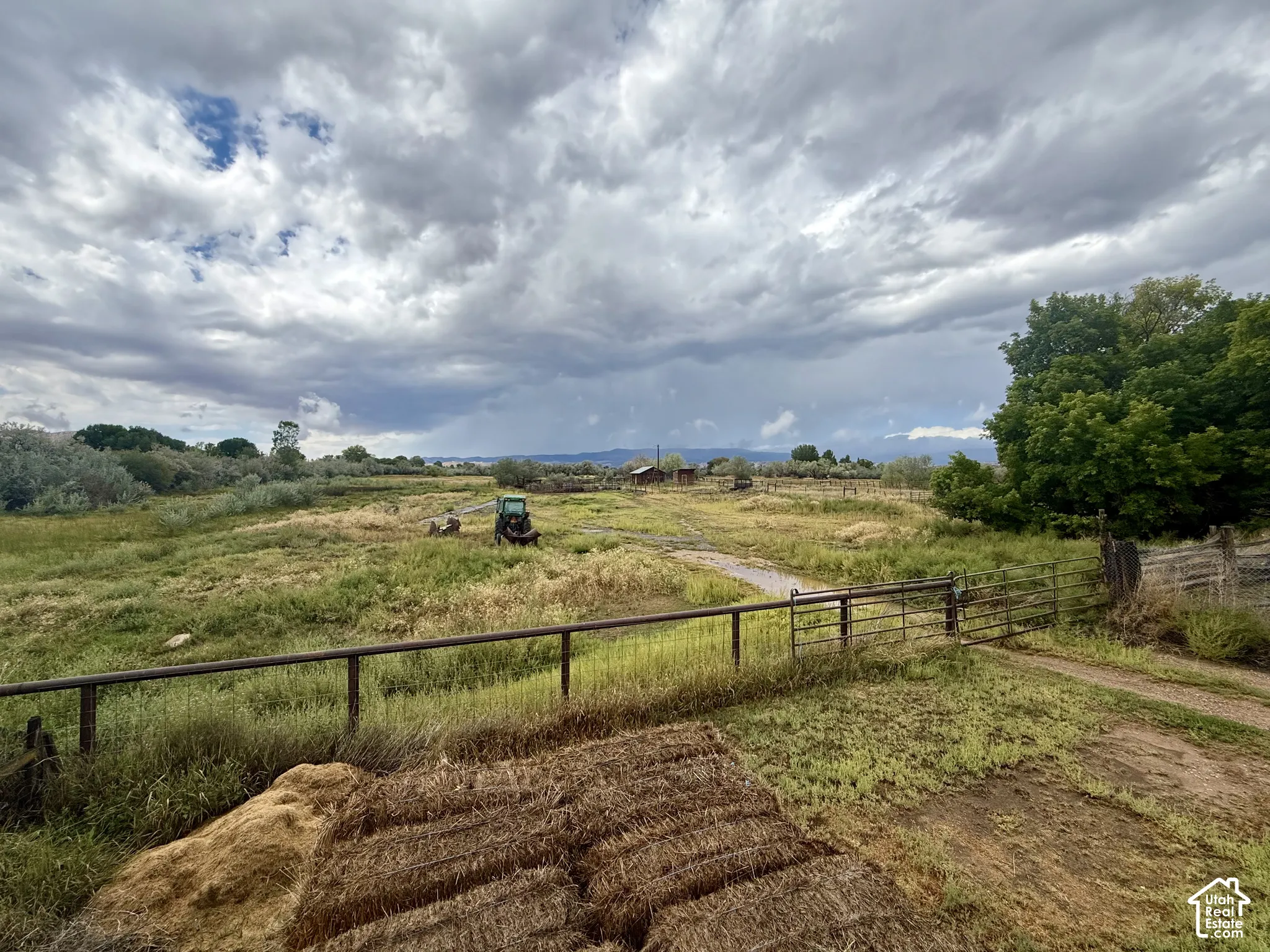 Expansive agricultural land featuring a natural landscape and a metal fence with gate
