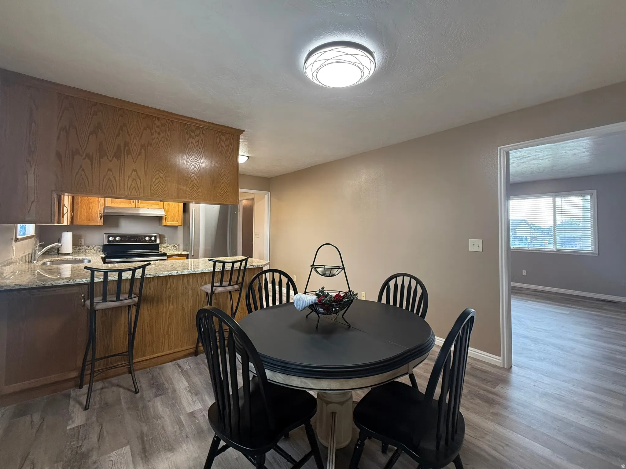 Kitchen featuring wood cabinetry, granite countertops, stainless steel appliances, and a breakfast bar
