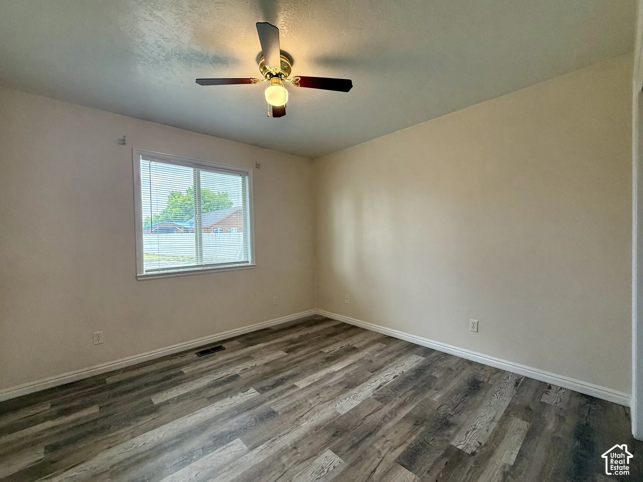 Wood-finish flooring, neutral wall tones, ceiling fan with integrated lighting, and a window with blinds