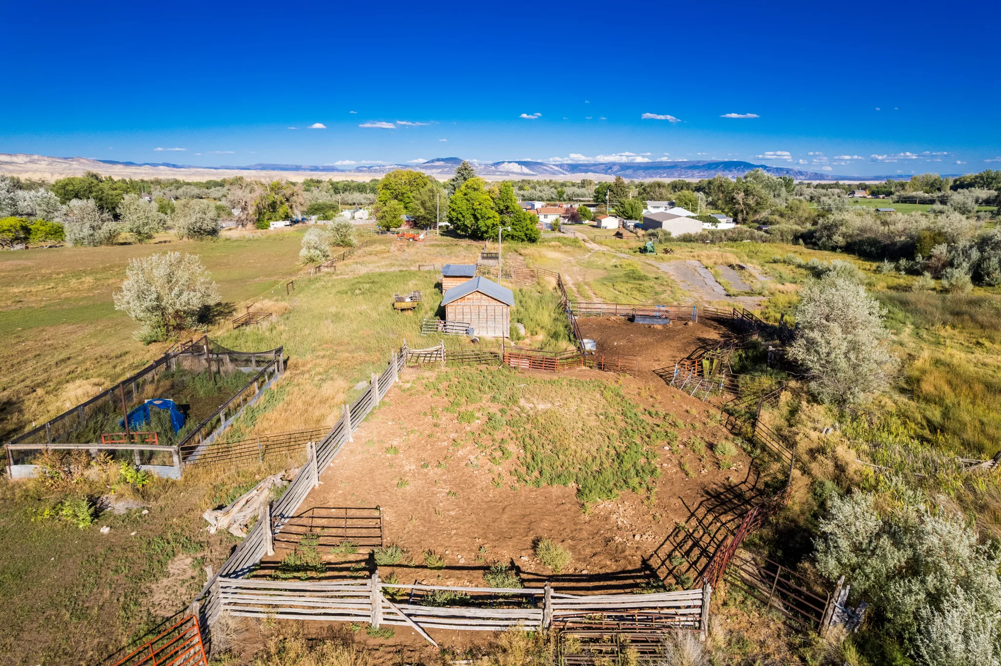 Expansive rural property featuring an agricultural outbuilding, fenced enclosures, and a large fenced recreation area