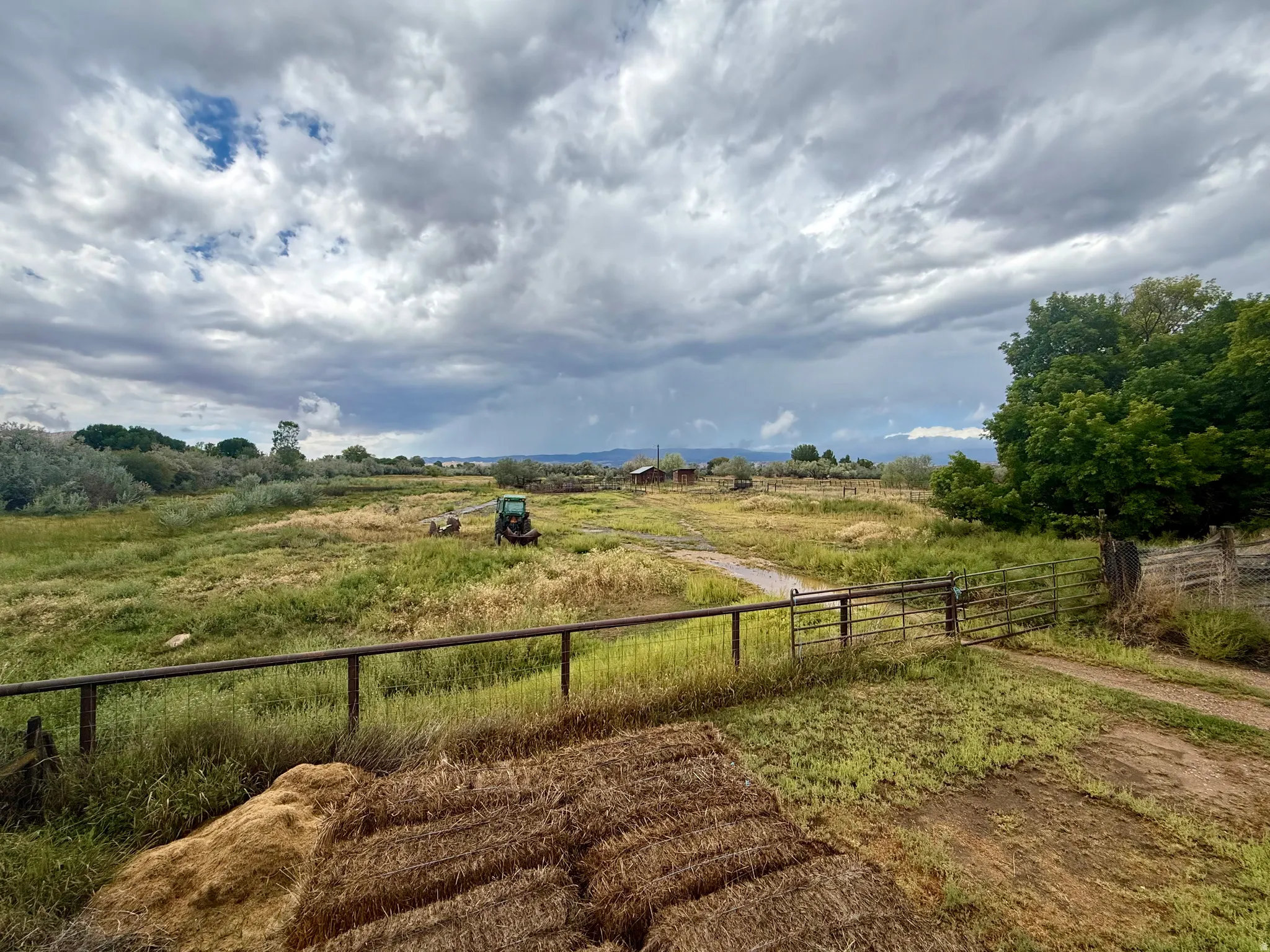 Expansive agricultural land featuring a natural landscape and a metal fence with gate