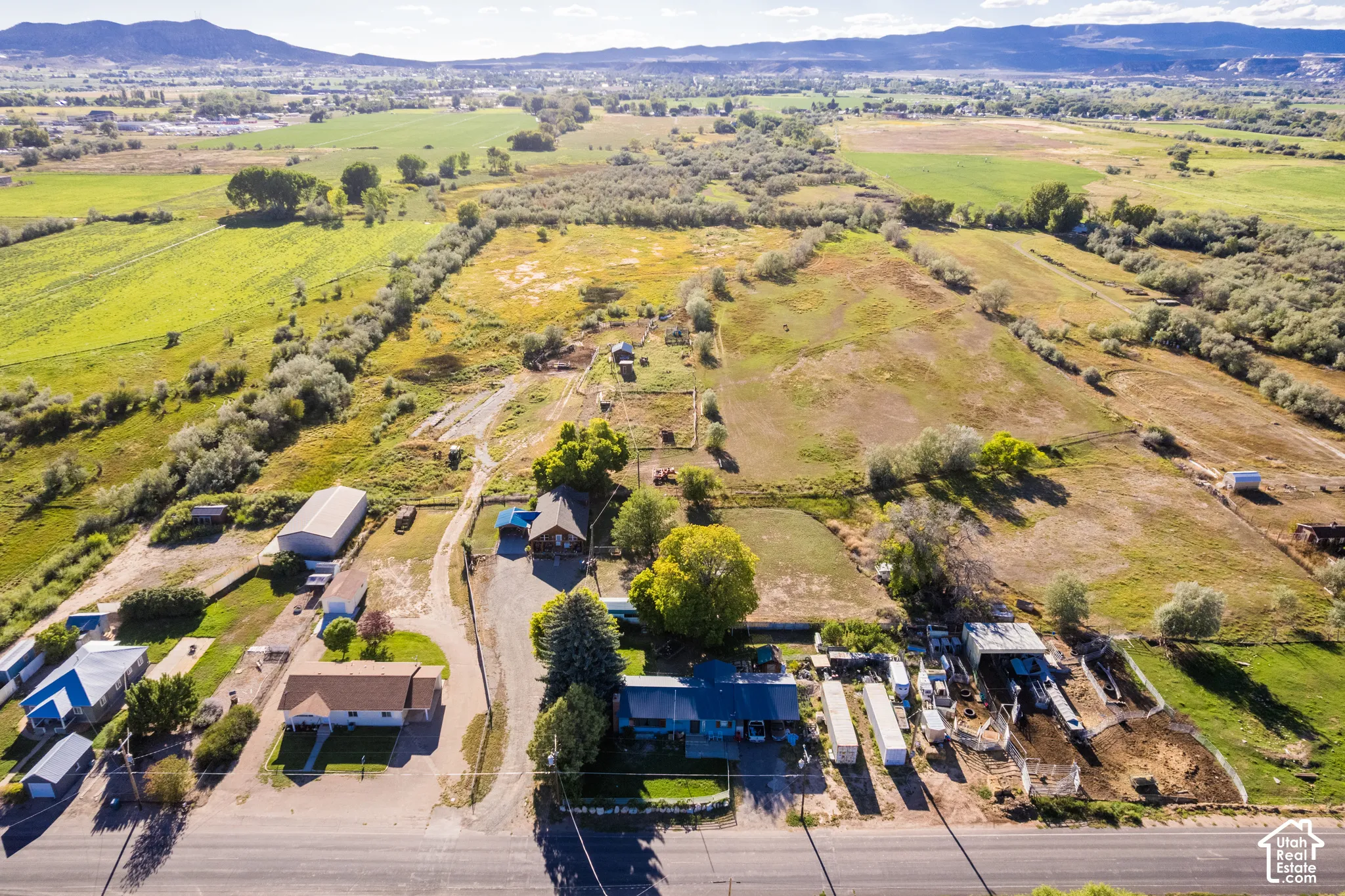 Expansive landscape featuring multiple structures, open fields, and surrounding natural foliage