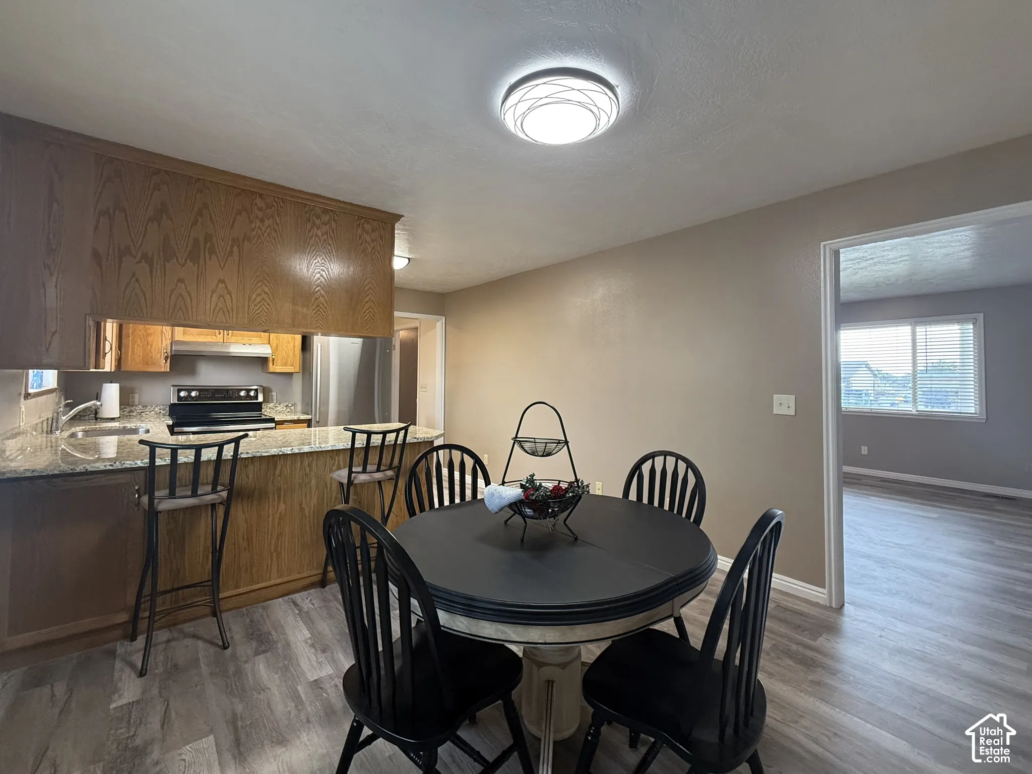 Kitchen featuring wood cabinetry, granite countertops, stainless steel appliances, and a breakfast bar