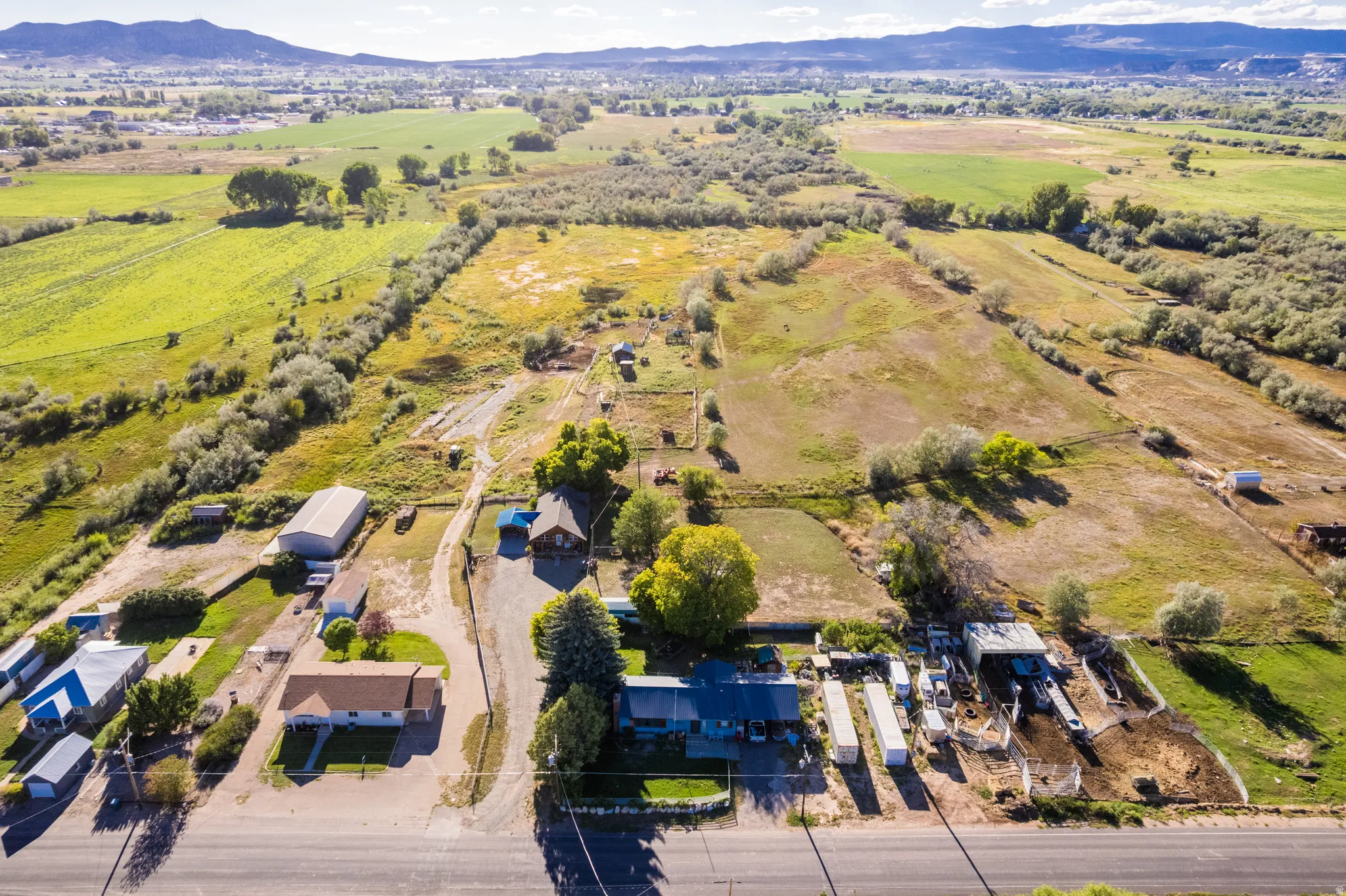 Expansive landscape featuring multiple structures, open fields, and surrounding natural foliage