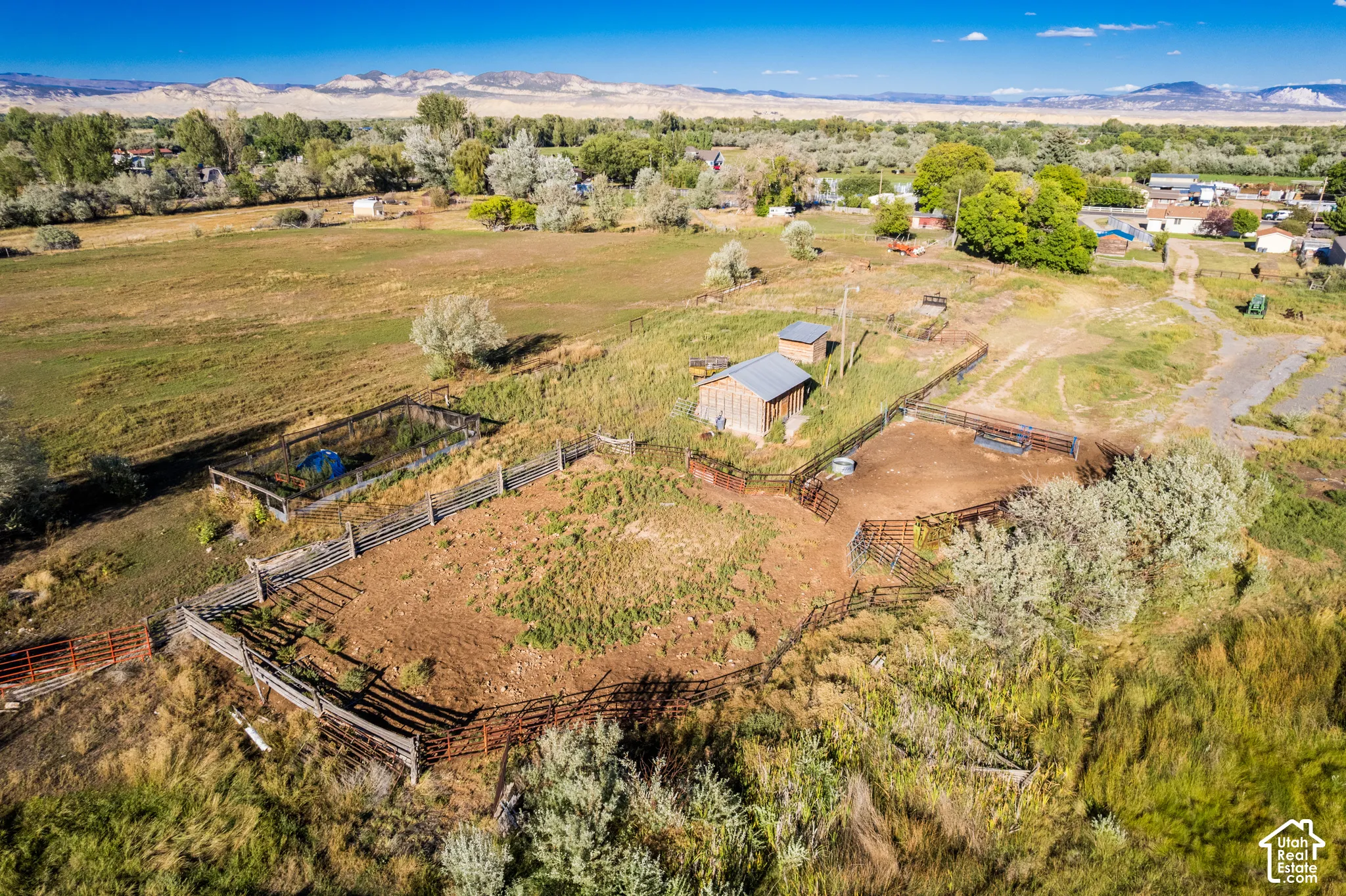 Multiple fenced areas, a detached outbuilding, expansive arid terrain, and distant natural scenery