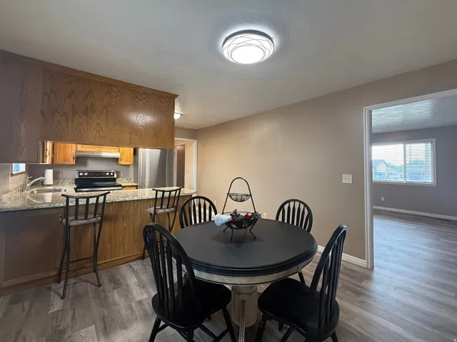 Kitchen featuring wood cabinetry, granite countertops, stainless steel appliances, and a breakfast bar