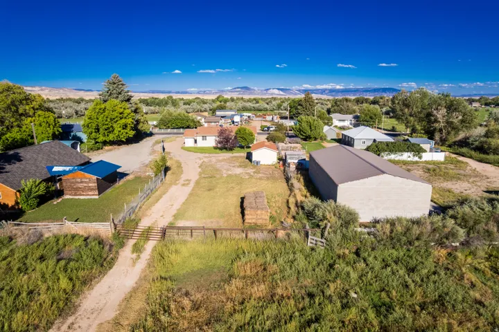 Expansive rural setting featuring a large metal-sided outbuilding, a fenced perimeter, and a dirt road entrance
