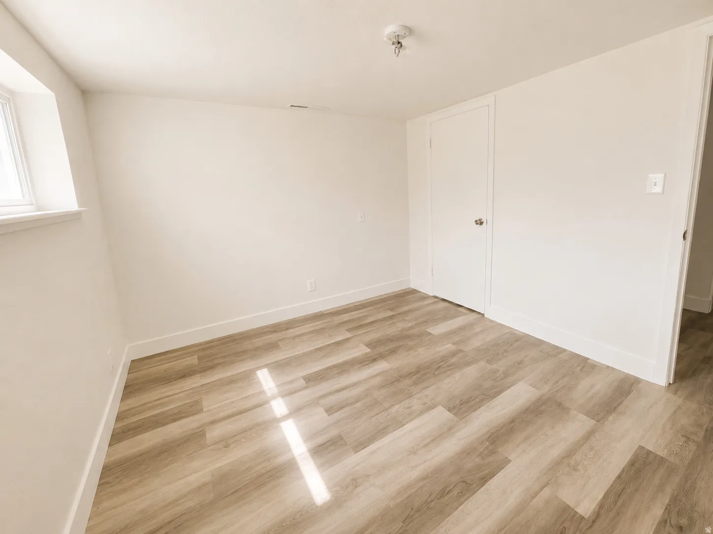Light wood-finish flooring, white walls, and a single window