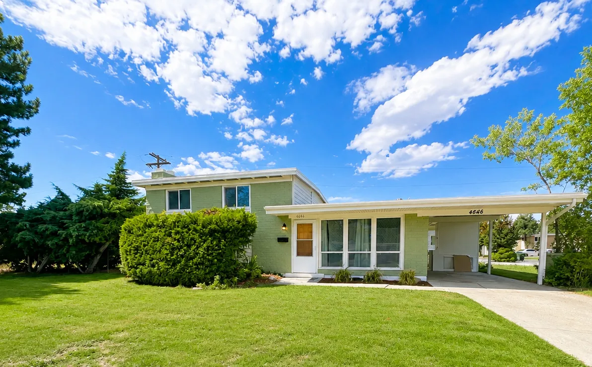 Split-level residence featuring a carport, front yard with mature landscaping, and a paved driveway