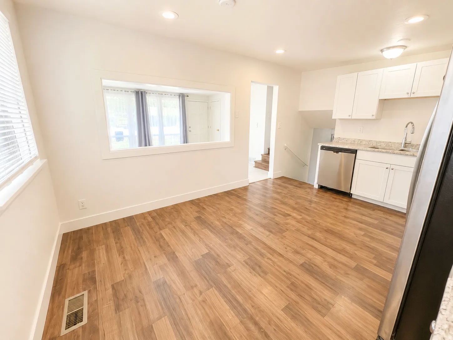 Wood-finish flooring throughout, white cabinetry, stainless steel dishwasher, and recessed lighting
