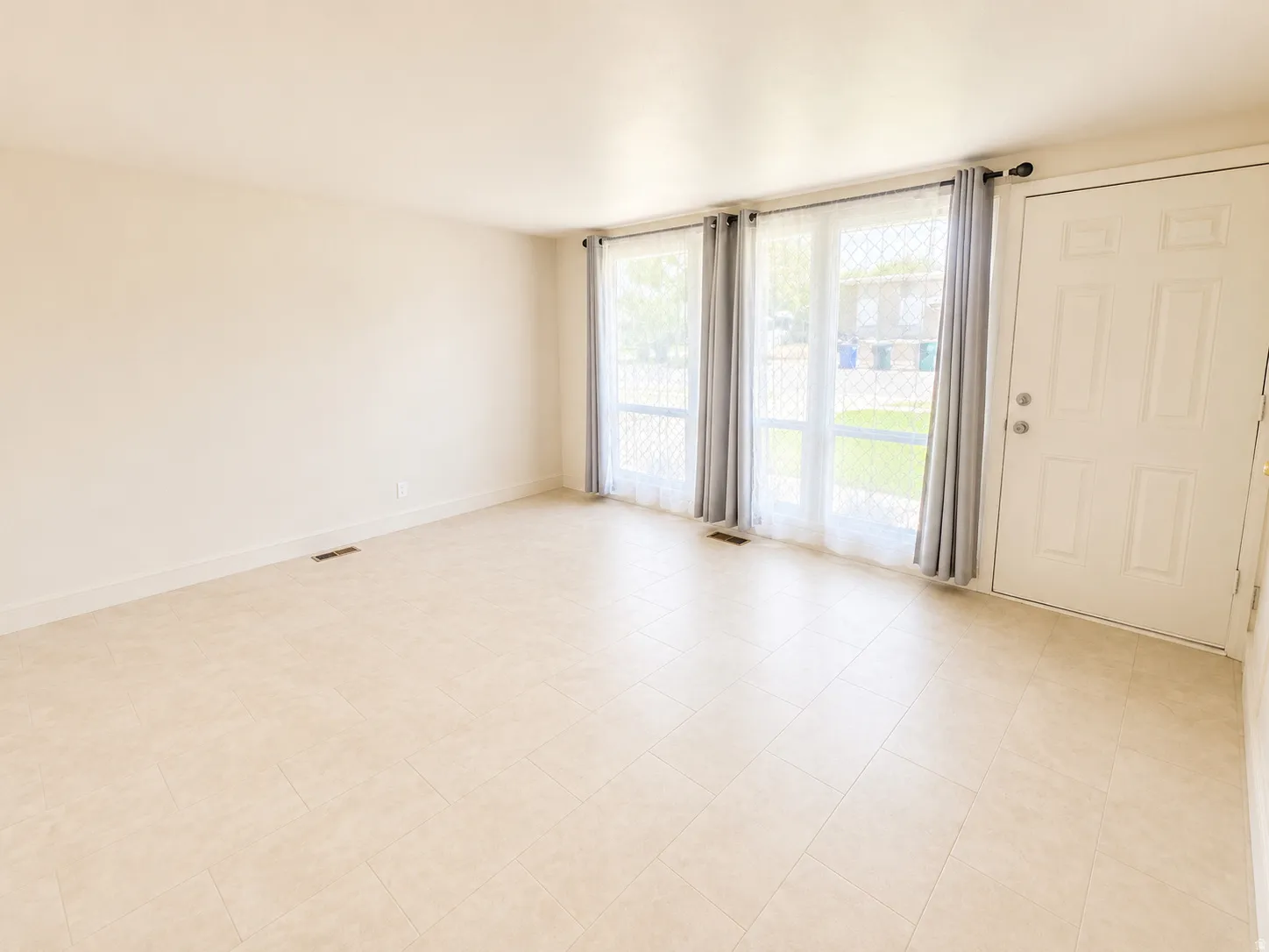 Neutral wall finish, light-toned tile flooring, and multiple window units
