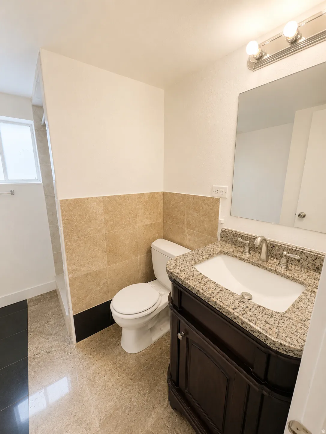 Bathroom featuring a dark wood vanity with a granite countertop, undermount sink, and brushed nickel faucet