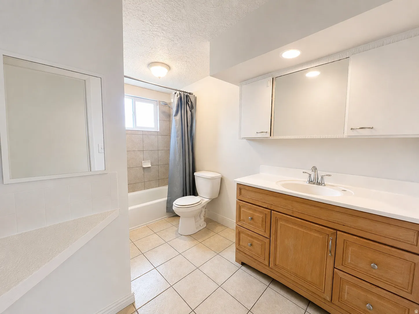Bathroom featuring a wood-finish vanity with a white countertop, an undermount sink, and chrome fixtures