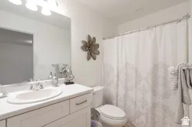 White vanity with a single basin sink, chrome faucet, and overhead three-bulb vanity light