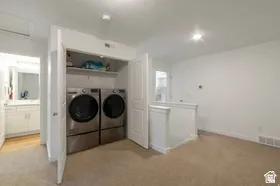 Dedicated laundry closet with built-in shelving, front-loading washer and dryer, and adjacent bathroom