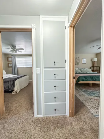 Built-in storage cabinet with four drawers and an upper cupboard, complemented by carpet flooring