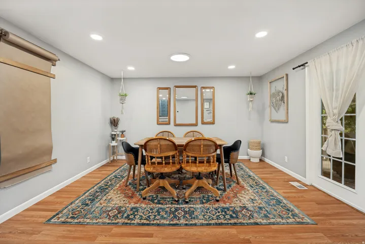 Recessed ceiling lighting, wood-finish flooring, light gray wall tones, and a paneled glass door