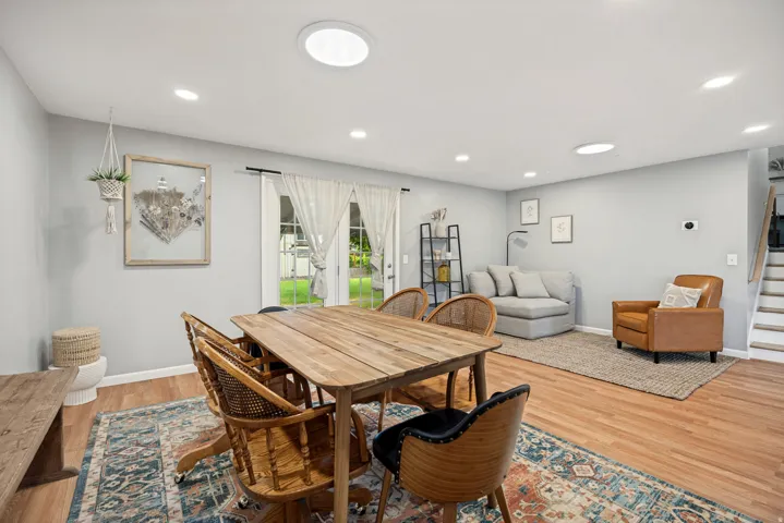 Recessed lighting, wood-finish flooring, light gray wall color, double glass panel doors, and a staircase with white risers