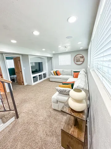 Recessed lighting throughout, carpeted flooring, built-in media center with shelving, and natural wood doors