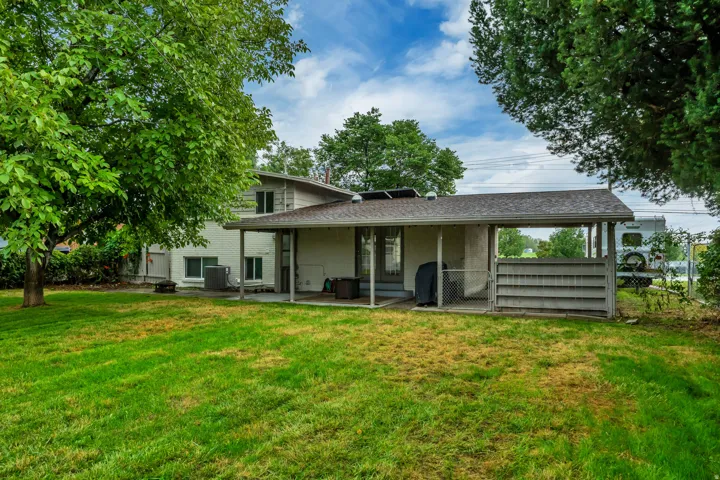 Expansive lawn area with mature trees, covered patio, and multi-level exterior architecture