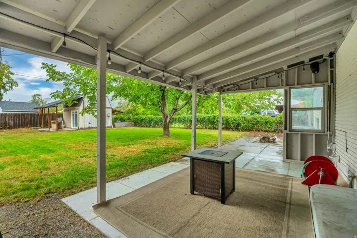 Covered patio with string lighting, concrete flooring, and a expansive grassy area