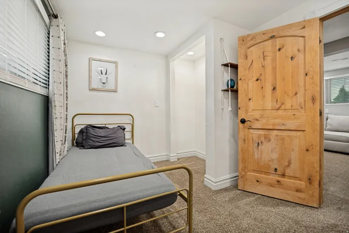 Recessed lighting, wood-finish interior door, hanging shelves, window with blinds, and carpeted flooring