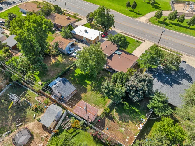 Expansive property featuring mature trees, multiple outbuildings, and a surrounding privacy fence