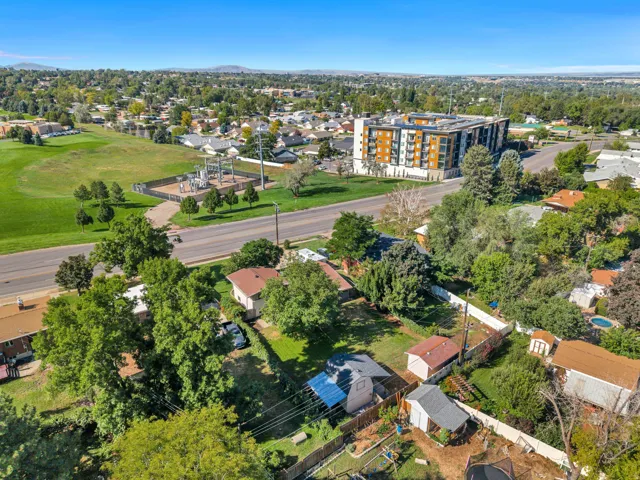 Aerial perspective showcasing residential properties with mature trees, green spaces, and a prominent multi-story building in the background