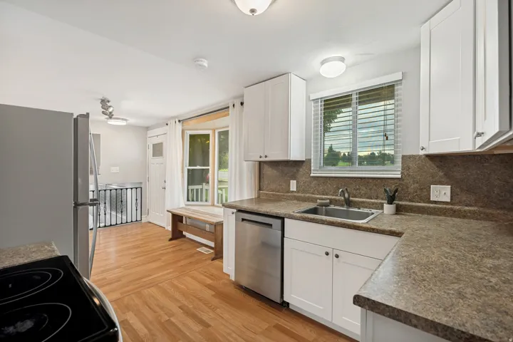 Kitchen featuring white cabinetry, stone-finish countertops, stainless steel appliances, and wood-finish flooring