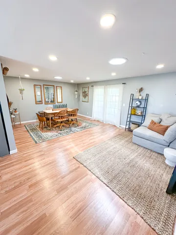 Recessed lighting, skylight, wood-finish flooring, light grey wall paint, and double glass panel doors