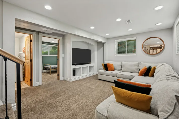 Recessed lighting illuminates the carpeted living area with a built-in media console
