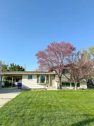 Property exterior with a carport, established landscaping, and a lawn