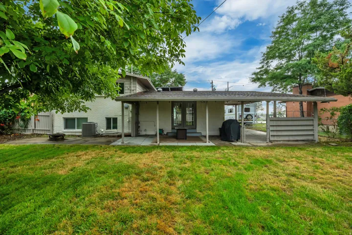 Covered patio area with a concrete slab, access to a paved driveway, and established trees