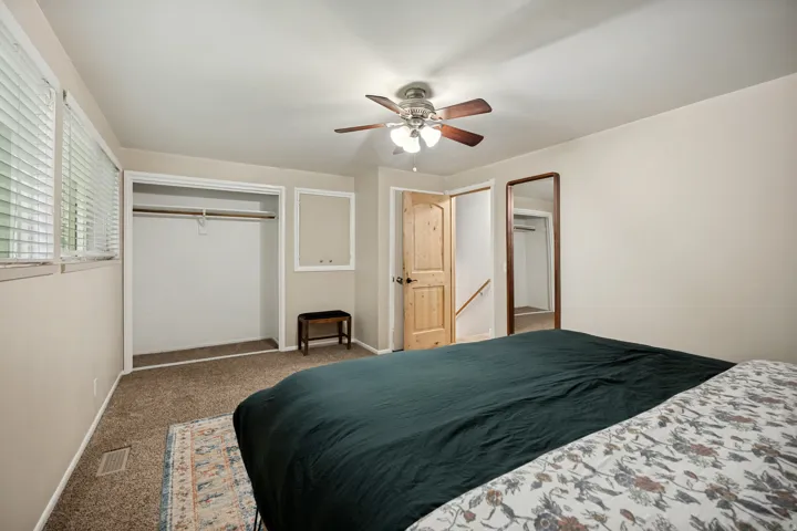 Wall-to-wall carpeting, wood-finish door, ceiling fan with light fixture, and window with blinds