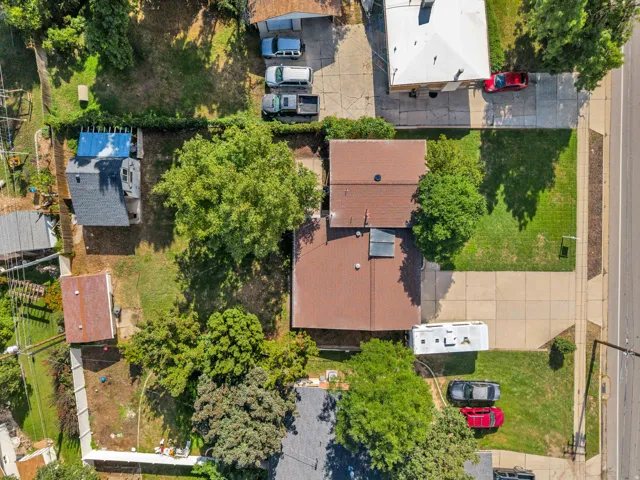 Property featuring a brown shingle roof, paved driveway, and mature trees